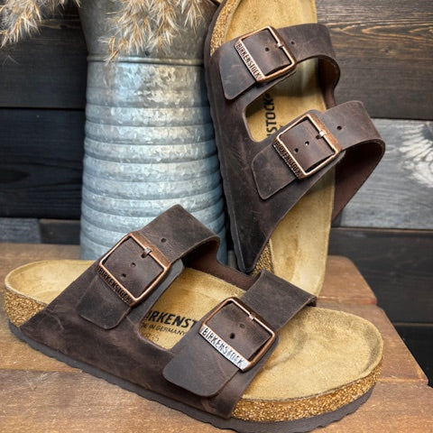 Brown suede sandals with leather straps on a wooden surface