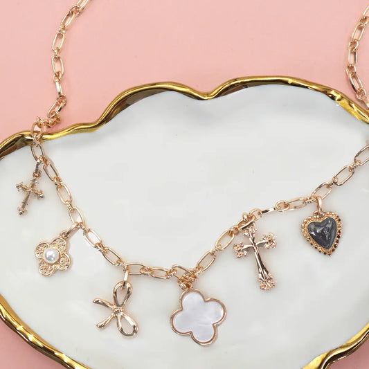 The Charm Necklace Porcelain Clover, Bow, Cross, Heart, Flower is a beautifully curated piece featuring delicate porcelain accents and an array of charming motifs, including a lucky clover, graceful bow, classic cross, romantic heart, and sweet flower. Product Details• length: 16.5"• charm size: varies .25" - 1"• ext: 3" Ball Chain Ext• clasp: Lobster Claw• metal finish: Gold Plated• product: Lead & Nickel Compliant• anti-tarnish: Double E-coating